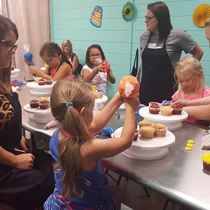 Kids decorating cakes at a party table