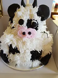 A cow-print cake with pink ears