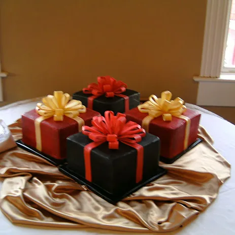 A cake made to look like a stack of wrapped presents with gold bows
